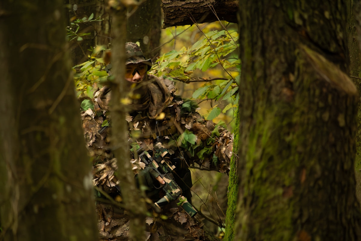 A man in camouflage walking through a forest